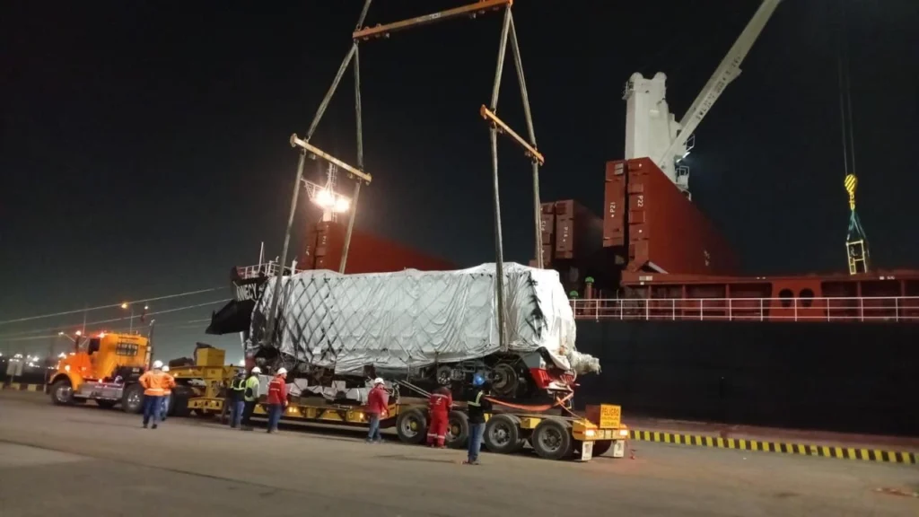 Jueves 21 de mayo de 2026. El proyecto RegioTram de Occidente continúa avanzando en su fase constructiva con la llegada al puerto de la ciudad de Barranquilla (Atlántico) de nueva maquinaria ferroviaria especializada que permitirá acelerar las obras de conformación de la vía férrea del 1er tren regional de pasajeros de Colombia. El gobernador del departamento de Cundinamarca, Jorge Emilio Rey Ángel, confirmó la llegada de una bateadora de última tecnología, 2 locomotoras auxiliares y 6 tolvas de balasto; equipos fundamentales para el desarrollo de los terraplenes y la instalación de la estructura ferroviaria sobre la que operará el sistema. “Acabamos de recibir en el puerto de Barranquilla una bateadora de última tecnología, 2 locomotoras auxiliares y 6 tolvas de balasto, las cuales van a permitir construir los terraplenes que soportarán la vía férrea del proyecto RegioTram de Occidente”. Señaló el 1er mandatario cundinamarqués. El gobernador Rey Ángel explicó que esta maquinaria tendrá un papel clave en la distribución y compactación del balasto, material rocoso que sirve de soporte estructural para la vía férrea y garantiza estabilidad y seguridad en la operación del tren. “Estas máquinas distribuirán y compactarán el balasto que dará forma al corredor férreo. Recordemos que el balasto es el material rocoso que sostiene el tren”, agregó Jorge Rey. Cada una de las tolvas tiene capacidad para movilizar 28 toneladas de material, lo que permitirá garantizar disponibilidad permanente de balasto en los diferentes frentes de obra y mantener continuidad en la ejecución del proyecto. La maquinaria está siendo trasladada desde Barranquilla hacia el patio taller El Corzo, ubicado en Facatativá (Cundinamarca), mediante 9 vehículos tipo cama baja. Se prevé que los equipos lleguen entre el viernes 22 y el lunes 25 de mayo de 2026. Actualmente, el proyecto RegioTram de Occidente ya supera los 180.000 metros cúbicos de material removido en excavaciones y cuenta con 12.000 metros cuadrados de subbase conformada para avanzar en la instalación del subbalasto y el balasto. De acuerdo con las proyecciones técnicas del proyecto, la meta es lograr la conformación de cerca de 300 metros lineales de vía férrea por día durante esta etapa constructiva. La llegada de esta maquinaria especializada marca un nuevo avance en la ejecución del sistema férreo que conectará a Bogotá con municipios de la provincia Sabana Occidente, consolidando una de las obras de infraestructura de movilidad más importantes del país.